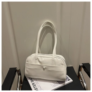 Close-up of a vintage white faux leather shoulder bag with decorative buckle on a chair