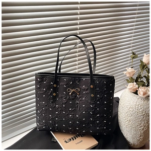 Détail du sac cabas noir à pois avec nœud métallique et décor floral élégant