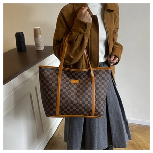 Detailed view of large checkered tote bag with leather strap and fashion label on model