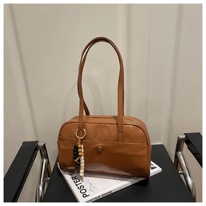 Macro detail of brown leather shoulder bag with decorative bead tassel and outer pocket