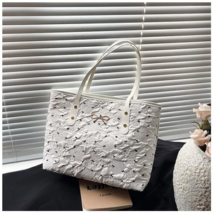 Détail du sac cabas plissé blanc avec motifs de nœuds noirs et garnitures dorées