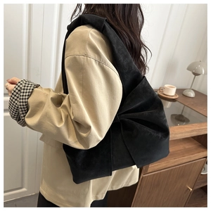 Elegant black velvet shoulder bag with side bow detail styled with a beige blazer