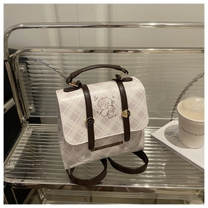 Détail du sac à carreaux avec illustration de chien et lanières en cuir marron