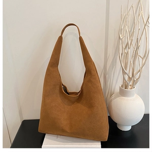 Detail of caramel brown suede hobo tote bag texture on minimalist white background