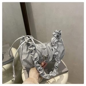 Detail of silver pleated crescent bag with elegant butterfly metal buckle on white base