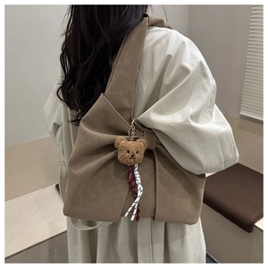 Vue latérale du sac fourre-tout marron en forme de nœud avec breloque ours en peluche