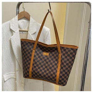 Detail of checkered tote bag with leather straps on a white blazer background