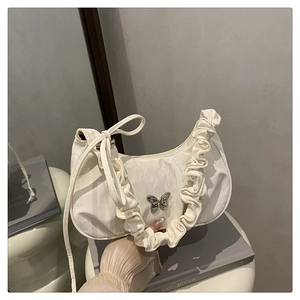 Detailed view of cream crescent bag with pleated edges and silver metal butterfly buckle