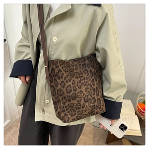 Close-up of leopard print tote bag with brown leather strap worn on the shoulder