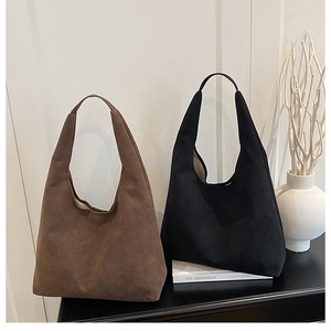 Detail of dark brown and black oversized suede tote bags in a minimalist interior setting