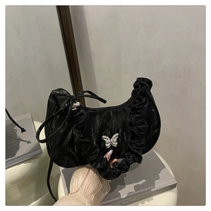 Detailed view of black pleated crescent bag with silver butterfly buckle and ruffles