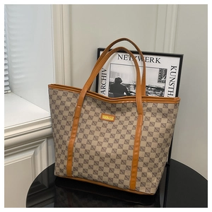 Detail of canvas tote bag with brown leather trim and geometric pattern on reflective surface