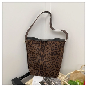 Detail of leopard print suede tote with wide leather strap on a woven chair