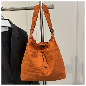 Detail of orange drawstring tote bag with textured fabric and adjustable wide shoulder strap