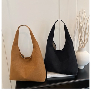 Close-up of minimalist suede hobo bags in black and brown with seamless stitching