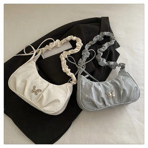 Detail of ruched crescent shoulder bags with metal butterfly accents in cream and silver