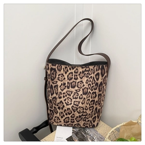 Macro detail of large leopard print bucket bag with brown strap on a white wall
