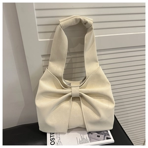 Detail of creamy white textured leather handbag featuring a large stylish bow design