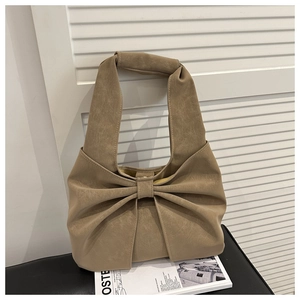 Close-up of khaki leather handbag with large bow detail and stone texture finish
