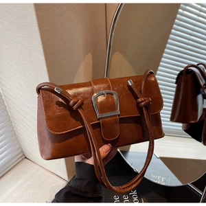 Close-up of vintage brown leather baguette bag with oversized silver buckle detail