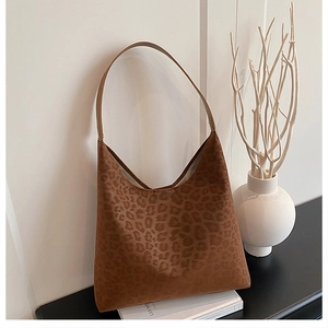 Detail of leopard print suede shoulder bag on minimalist decorative book background