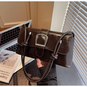 Detail of vintage brown oil wax leather bag with large silver buckle and slim strap