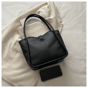Detail of black matte leather tote bag with vertical stitching and snap closure