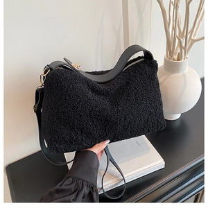 Detail of black faux shearling tote bag with leather handles and gold metal hardware