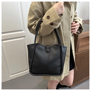 Close-up detail of high-quality black leather tote bag with elegant shoulder straps