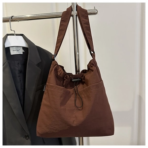 Detail of dark brown nylon tote with drawstring closure and fashion woven label