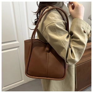Brown leather tote bag featuring matte texture and vintage aesthetic on model shoulder