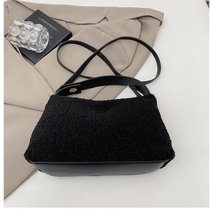 Close-up of black plush shearling texture and gold hardware on a minimalist shoulder bag