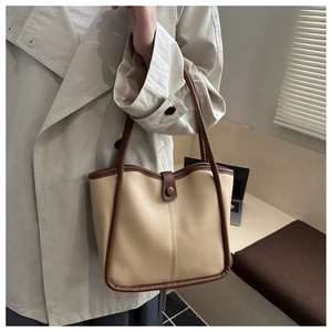 Detail of a two-tone beige and brown bucket bag shown in a stylish office setting