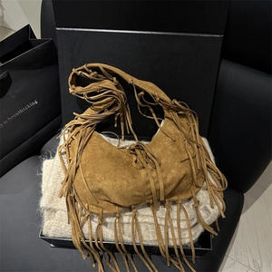 Bohemian brown suede tote bag with fringe tassels on black gift box background
