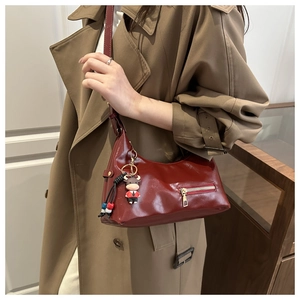Detail of burgundy oil wax leather shoulder bag with a cute cow keychain pendant