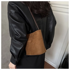 Brown suede bucket bag with leopard print texture worn by model in a black leather jacket