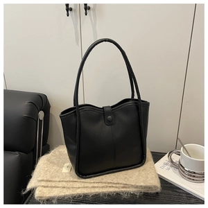 Detail of minimalist black tote bag with wavy top edge and stylish long handles
