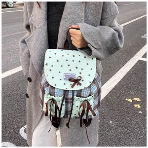 Detail view of plaid canvas backpack with bow accents and star prints on pockets