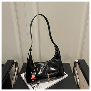 Close-up of black patent leather hobo bag with a red cartoon cow charm pendant