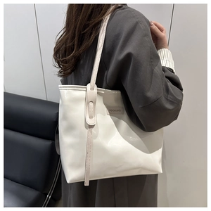 Close-up of a white leather tote bag showing the fashion label detail on the side