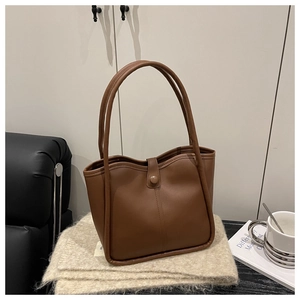 Detail of dark brown tote bag with wavy top opening on a cozy knit blanket