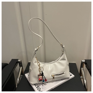 Detail view of a white crescent shoulder bag with metallic zipper and cartoon cow charm