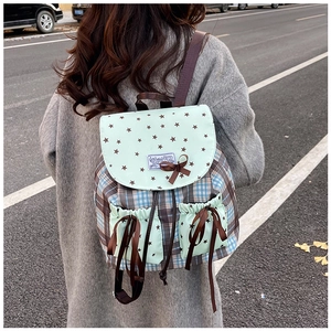 Detail of mint green flap with brown stars and bow on a plaid canvas backpack