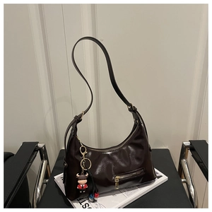 Detail of dark brown glossy hobo bag with adjustable strap and cute cow charm