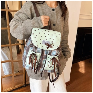 Detail of school backpack featuring mint green star print flap and brown ribbon bow