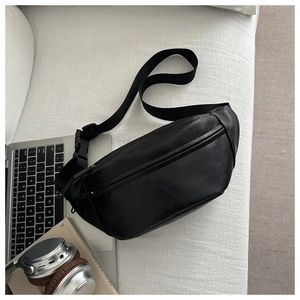 Flat lay of a black PU leather crossbody chest bag on a sofa with lifestyle accessories