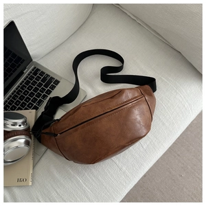Close-up of brown litchi pattern waist bag on beige sofa with lifestyle accessories