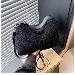 Detail of black plush teddy fabric texture with leather strap and golden buckle accents