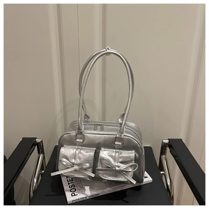 Detail of silver metallic handbag featuring bow-tie pockets and smooth zipper closure