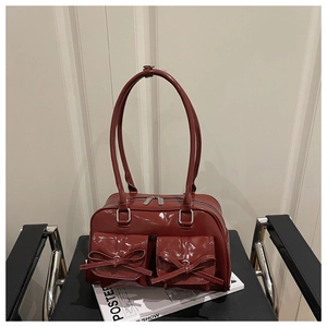 Detail of dark red patent leather handbag featuring chic bow pockets and glossy finish